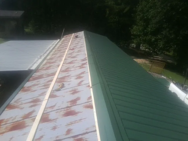 Old rusted panels beside newly installed green metal roofing — Wind Damage Roof Repair by Roofing Brothers in Gillette